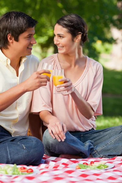 Dos amigos sonriendo mientras tocan vasos de jugo durante una foto —  Fotos de Stock