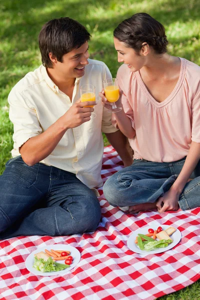 Two friends smiling as they raise their glasses of juice during — Stock Photo, Image
