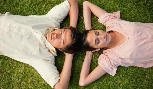 Two friends lying head to head with both hands behind their neck — Stock Photo, Image