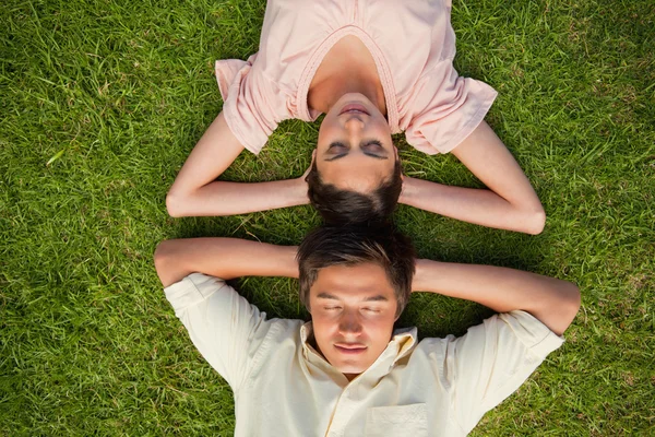 Frau und Mann liegen Kopf an Kopf, beide Hände hinter ihren Händen — Stockfoto
