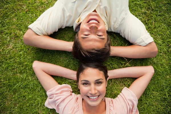 Two friends smiling while lying head to head with both hands beh — Stock Photo, Image