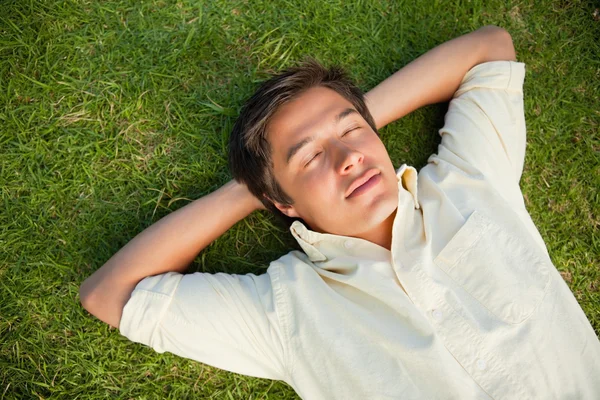 Man lying with his eyes closed and both hands behind his neck — Stock Photo, Image