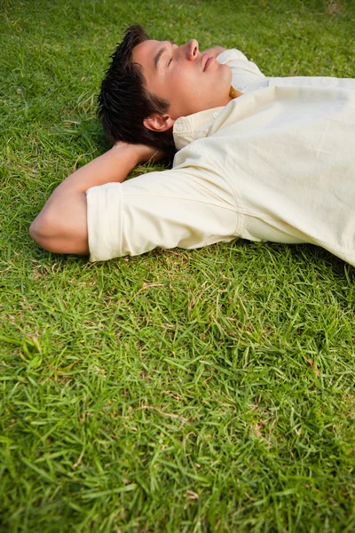 Мужчина лежит в траве с закрытыми глазами и обеими руками за привет — стоковое фото