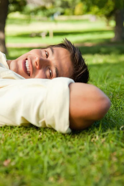 Hombre sonriendo mientras está acostado con el lado de su cabeza descansando sobre su —  Fotos de Stock