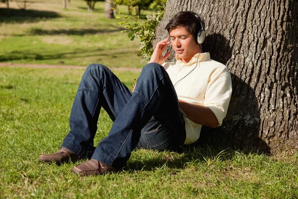 Hombre escuchando música a través de auriculares mientras descansa — Foto de Stock