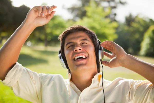 Hombre levantando los brazos mientras usa auriculares para cantar junto a mus — Foto de Stock