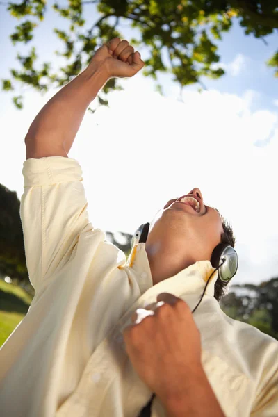Hombre levantando su brazo mientras usa auriculares para escuchar música en — Foto de Stock