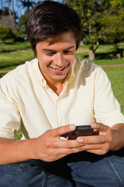 Man using a phone while he is sitting down — Stock Photo, Image