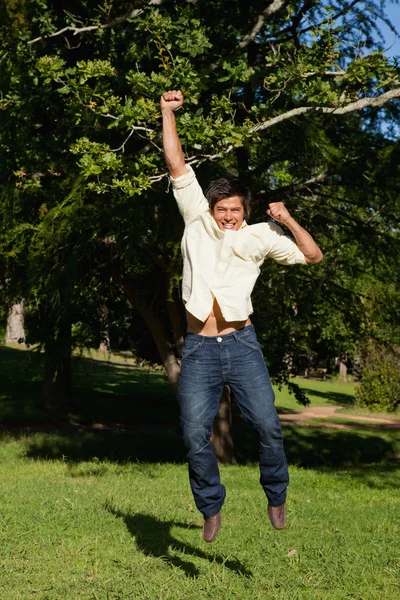 Man springen met zijn armen verhoogd zoals hij verheugt zich — Stockfoto