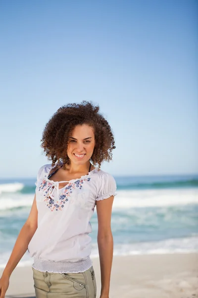 Молодая улыбающаяся женщина стоит на пляже — стоковое фото