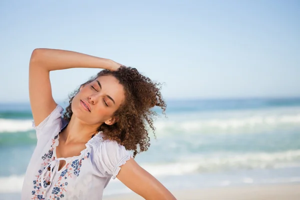 Молода жінка закриває очі, стоячи на пляжі — стокове фото