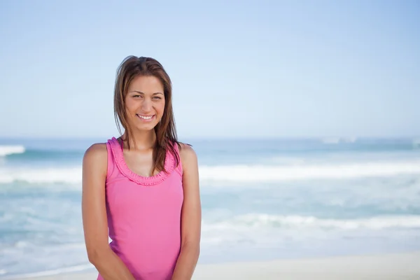 Jovem mulher sorridente em pé em frente ao mar — Fotografia de Stock