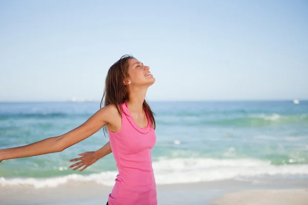 年轻女子直立在沙滩上享受日光浴的同时 — 图库照片