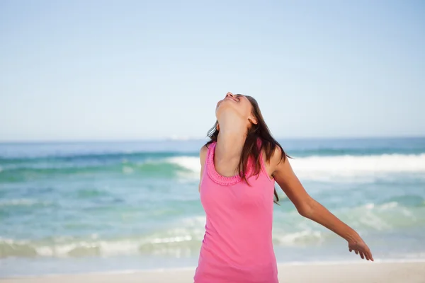 Jovem mulher relaxada de pé na praia enquanto toma sol — Fotografia de Stock
