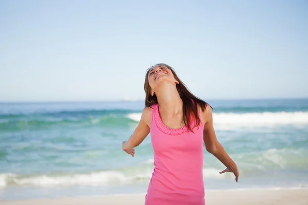 Mladá usměvavá žena užívat slunce, zatímco stojící na pláži — Stock fotografie