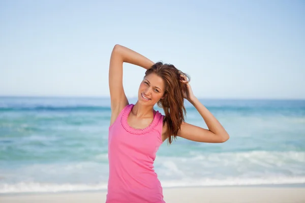 若い女性のビーチで彼女の頭の後ろに彼女の手を置くこと — ストック写真
