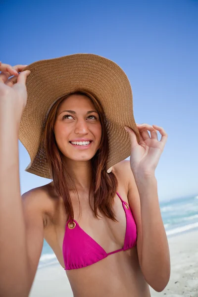 Smiling attractive teenager holding her hat brim in front of the — Stock Photo, Image