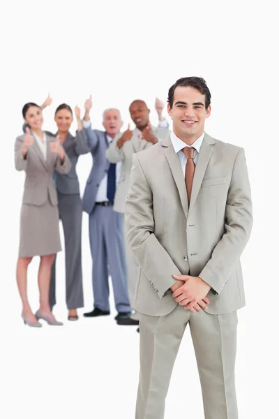 Smiling businessman with cheering team behind him — Stock Photo, Image