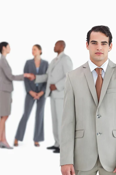 Serious salesman with businesspeople behind him — Stock Photo, Image
