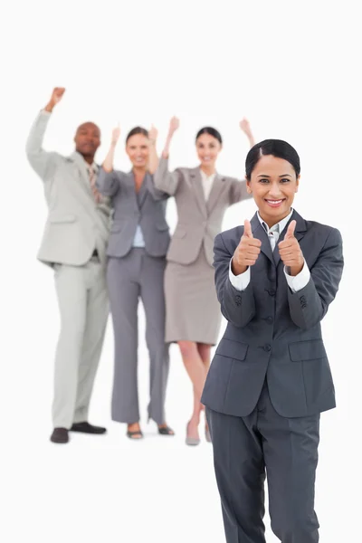 Saleswoman with cheering team behind her giving thumbs up — Stock Photo, Image