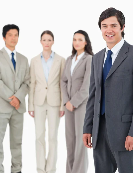 Smiling young salesman with his team behind him — Stock Photo, Image