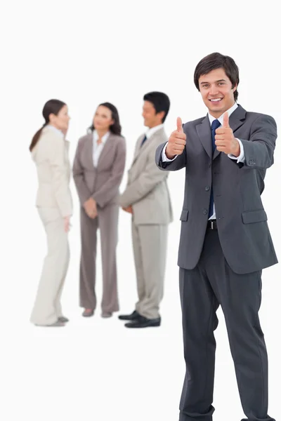 Salesman giving thumbs up with colleagues behind him — Stock Photo, Image