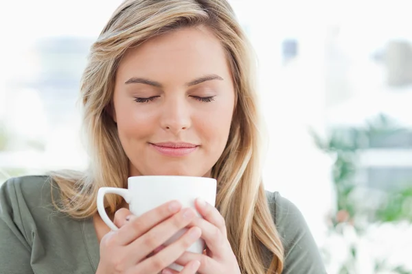 Woman with mug raised to near her mouth, eyes closed and smiling — Stock Photo, Image