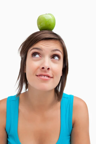 Attractive young woman standing upright with a green apple on he — Stock Photo, Image