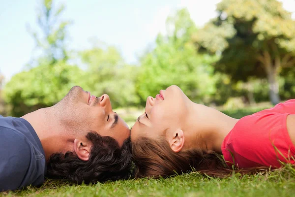 Two friends with their eyes closed while lying head to head Royalty Free Stock Images