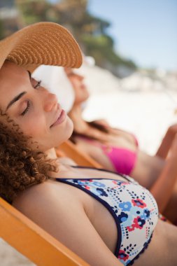 Beautiful woman napping on the beach on a deck chair clipart