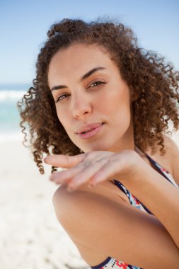 Young woman sending an air kiss while blowing on her hand clipart