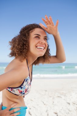 Happy young woman placing her hand on her forehead to look far a clipart