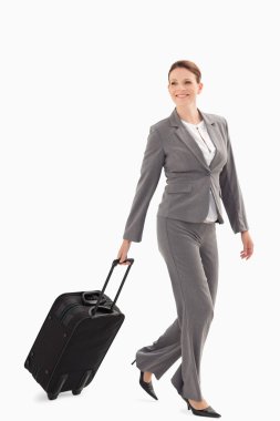 Smiling businesswoman walking with a suitcase clipart