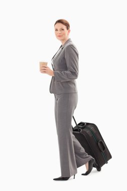 Businesswoman walking with coffee and suitcase clipart