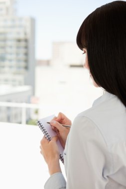 A woman with her back turned begins to write down some informati clipart