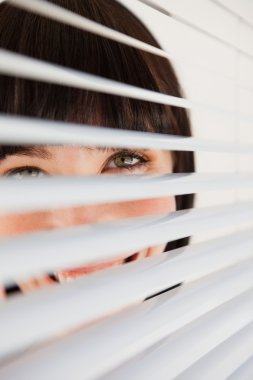 A smiling business woman looking through her blinds clipart