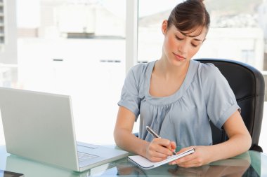 A woman takes down notes on her notepad clipart