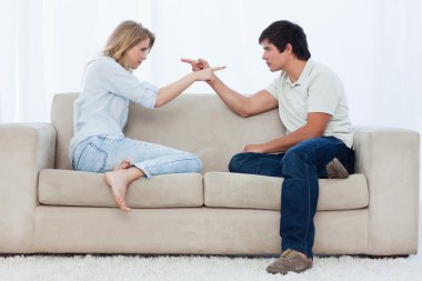 A couple sitting on a couch are pointing at each other clipart