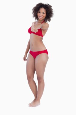 Smiling woman in swimsuit placing her thumbs up clipart