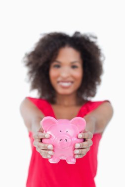 Pink piggy bank being held by a brunette woman clipart