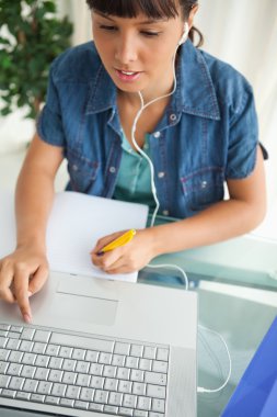 Female student doing his homework while helping with a netbook clipart