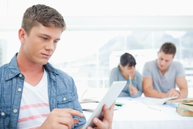 A man with a tablet pc works in front of his friends clipart