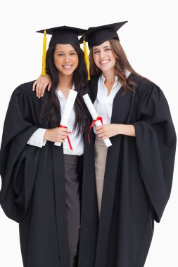 Two women embracing each other after they graduated from univers clipart