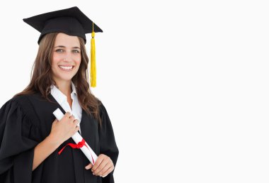 A smiling woman with a degree in hand as she looks at the camera clipart