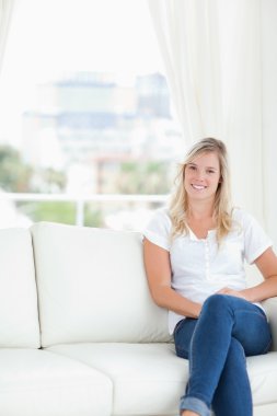 A smiling woman with her legs crossed clipart