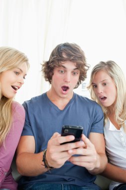 Shocked friends look at the man's phone clipart