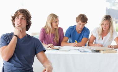 A young man sitting in front of his working class mates and thin clipart