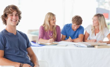 Smiling man sitting on front of his friends and looking at the c clipart