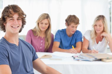 Close up of a smiling man sitting in front of his friends clipart