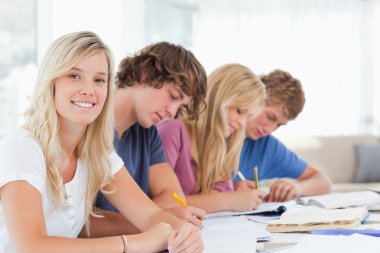 Students working as one girl smiles and looks at the camera clipart